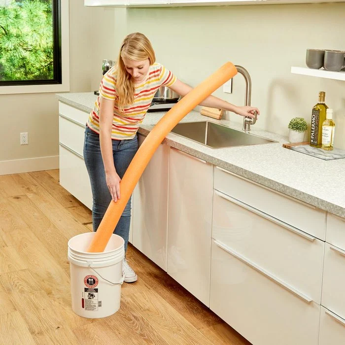 Lady filling bucket with pool noodle